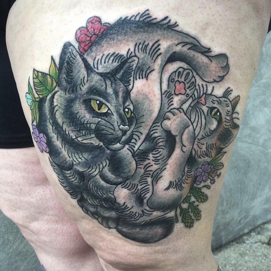 Two cats tattooed on a woman's thigh