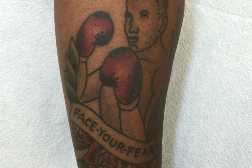 A tattoo of a fighter on an African American's left forearm